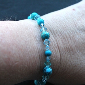 May include: A turquoise and clear crystal beaded bracelet. The bracelet is made with round turquoise beads and clear crystal beads.