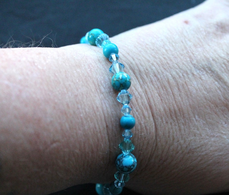 May include: A turquoise and clear crystal beaded bracelet. The bracelet is made with round turquoise beads and clear crystal beads.