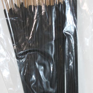 May include: A clear plastic bag filled with a bundle of black incense sticks. The sticks are tied together with a thin brown string.