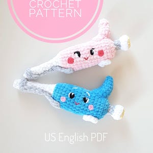 May include: Two crocheted amigurumi pipette toys. One is pink with a grey top and the other is blue with a grey top. Both have white eyes and pink cheeks. The text "AMIGURUMI PIPETTE CROCHET PATTERN US English PDF" is below the toys.