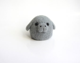 Liten söt kawaii manat, nåltovad sjöko. Tovad leksak. Figurer, skulpturer och djur.