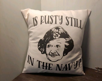 May include: White pillow with black text and a black and white image of a woman. The text reads "Is Rusty Still In The Navy?"