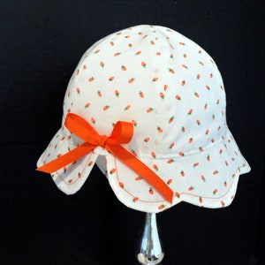 May include: White sun hat with an orange bow and a small carrot print.