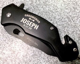 May include: Black pocket knife with a silver engraved inscription that reads "Groomsman Joseph 11.27.20" and a small bowtie symbol.