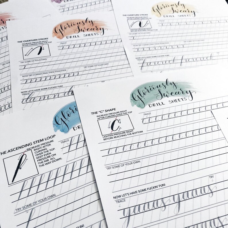 May include: Several white drill sheets for calligraphy practice are arranged on a surface. Each sheet features instructions for different strokes, with the words "Gloriously Sweary Drill Sheets" at the top. The sheets include examples and space for practice.