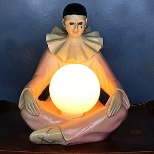 May include: A white ceramic mug with a black handle and the text "But First, Coffee" in a bold, black font. The mug is set against a blurred background, highlighting its simple design.