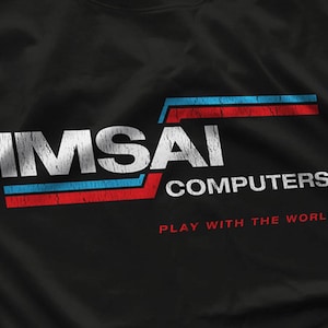 May include: Black t-shirt featuring the IMSAI COMPUTERS logo in white, with blue and red stripes. The text "PLAY WITH THE WORLD" is in red below the logo. The design has a vintage, distressed look.