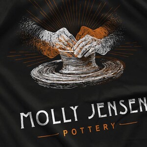 May include: Black fabric with a white and orange illustration of hands shaping clay on a pottery wheel. The text "MOLLY JENSEN POTTERY" is printed in white with an orange line below.