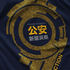May include: A navy blue t-shirt with a gold circular design featuring a circuit board pattern. The design includes the text "Public Security", "公安" (Chinese characters for "Public Security"), and "新居浜" (Japanese characters for "Niihama").