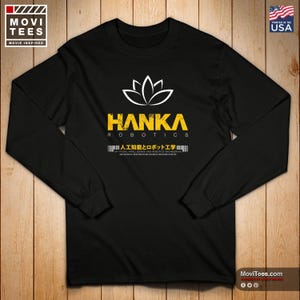May include: Black long-sleeve shirt with the text "HANKA ROBOTICS" in yellow and white. The shirt also features Japanese text and the words "Artificial Intelligence and Robotics Engineering". The shirt is printed in the USA.