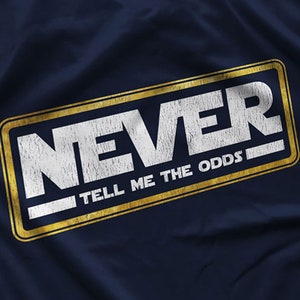 May include: A navy blue t-shirt with a gold and white graphic that says "NEVER TELL ME THE ODDS".