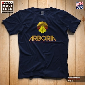 May include: A navy blue t-shirt with a retro-style graphic of a pyramid with a sun setting behind it. The text "Arboria Serenity Through Technology" is printed below the graphic.