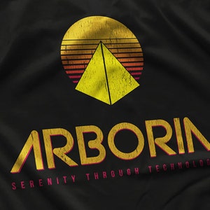 May include: A black t-shirt with a yellow and red retro-style logo that says "Arboria Serenity Through Technology". The logo features a yellow pyramid inside a red and yellow sun.