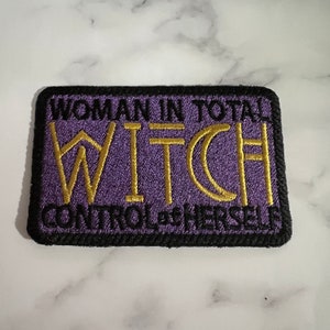 May include: Purple embroidered patch with black trim. The text reads "Woman in total control of herself, Witch".