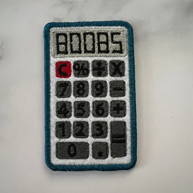 May include: A blue calculator patch with a white background and black numbers. The calculator has a display that reads "00005" and buttons for numbers 0-9, plus, minus, multiply, divide, and clear.