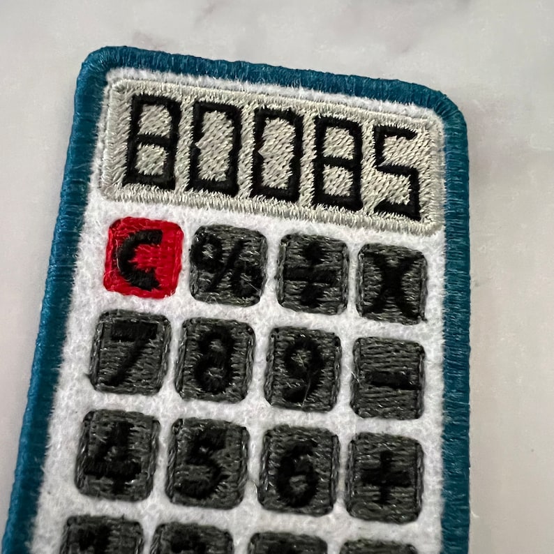 May include: A blue and white embroidered calculator patch with a red C button and the number 0005 displayed on the screen.