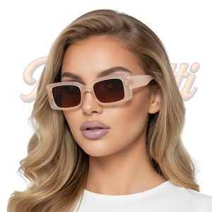 May include: Beige-framed sunglasses with dark brown lenses. The sunglasses have a rectangular shape and a thick frame. The image shows a close-up of the sunglasses, highlighting their design and color.