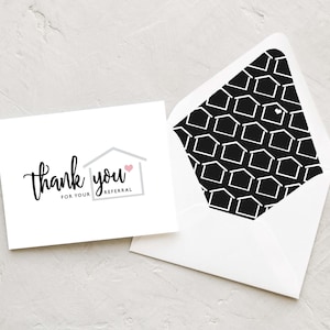 May include: A white thank you card with a gray house icon and a pink heart. The text on the card reads "thank you for your referral". The card is on a white envelope with a black and white pattern of houses.