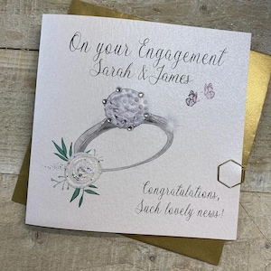 K&ouml;nnte beinhalten: Eine wei&szlig;e Karte mit einer Illustration eines silbernen Rings und eines Diamanten. Die Karte sagt "On your Engagement Sarah & James" und "Congratulations, Such lovely news!"