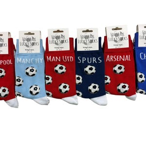 Puede incluir: Seis pares de calcetines de fútbol con nombres de equipos: Liverpool, Man City, Man Utd, Spurs, Arsenal y Chelsea. Cada par presenta patrones de balones de fútbol y colores del equipo.