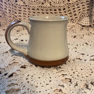 Pu&ograve; includere: Una tazza in ceramica con corpo color crema e base e manico marroni. La tazza ha un design semplice e classico, adatta per caff&egrave; o t&egrave;. Il manico &egrave; curvo e facile da impugnare.