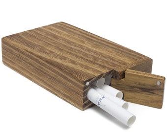 Puede incluir: Una caja de madera para cigarrillos con una tapa con bisagras, abierta para revelar un compartimento con varios cigarrillos en su interior. La caja está hecha de madera marrón oscura con un patrón de veta natural.