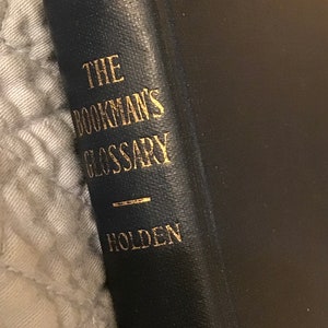 May include: A black book with gold lettering on the spine. The title is "The Bookman's Glossary" by Holden.