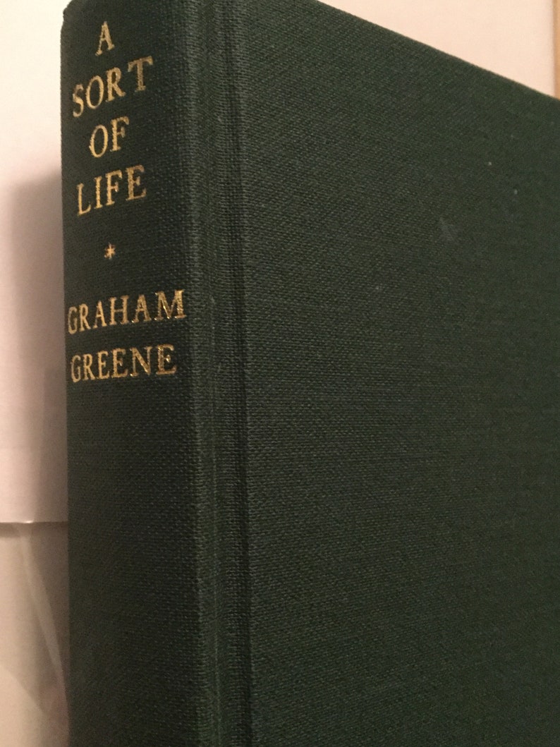 May include: A green hardcover book with the title "A Sort of Life" by Graham Greene printed in gold lettering.