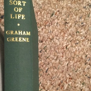 May include: A green hardcover book with gold lettering on the spine. The title is "A Sort of Life" by Graham Greene.