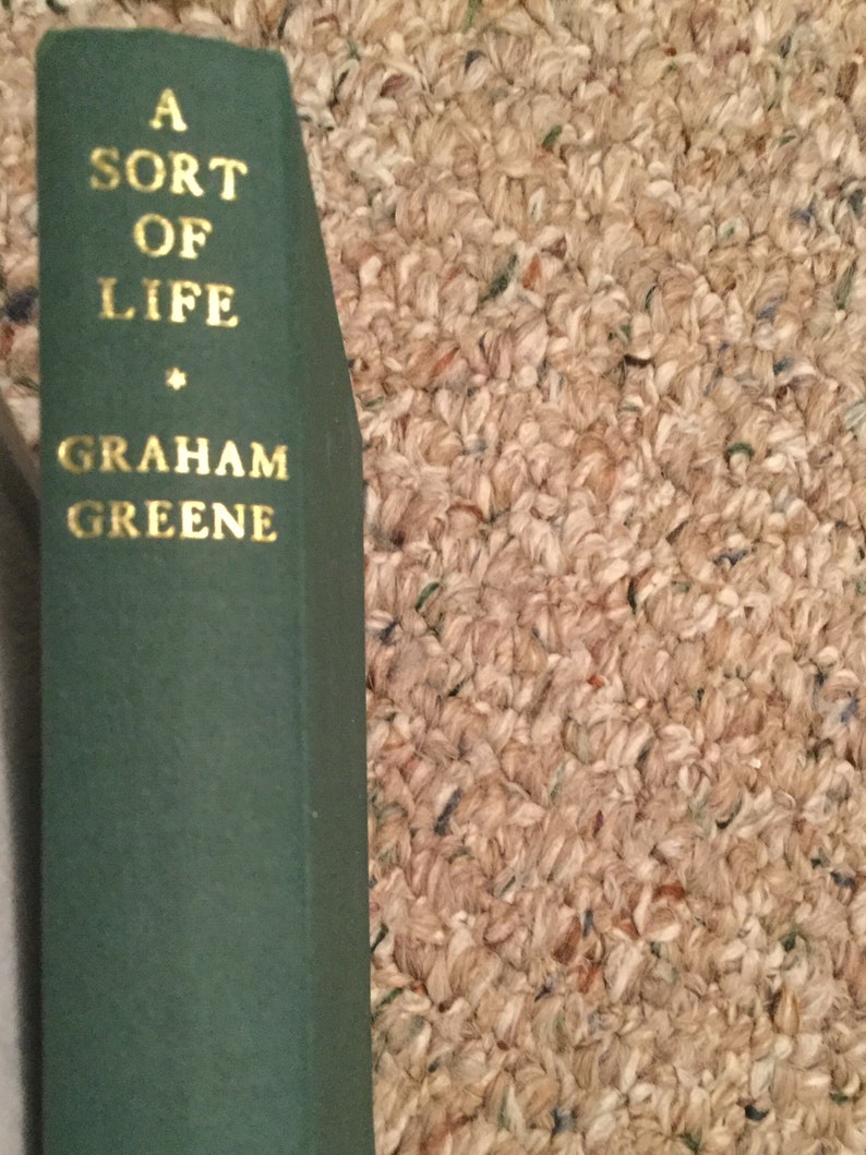 May include: A green hardcover book with gold lettering on the spine. The title is "A Sort of Life" by Graham Greene.