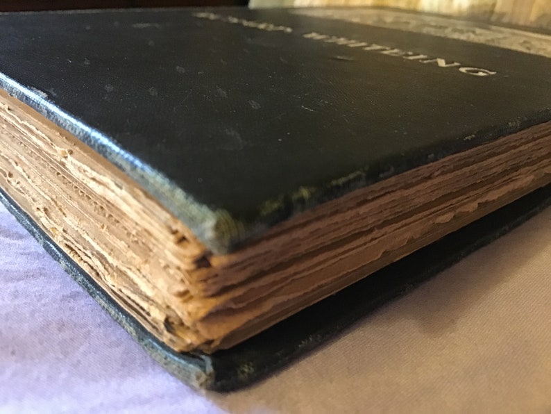 Op de afbeelding: Close-up van de rug van een zwart hardback boek met gouden letters die "The Writings" lezen. Het boek is oud en de pagina's zijn vergeeld.