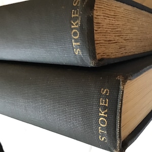 May include: Two dark blue hardcover books with gold lettering. The top book says "STOKES" and "VOLUME I". The bottom book says "STOKES" and "VOLUME II".