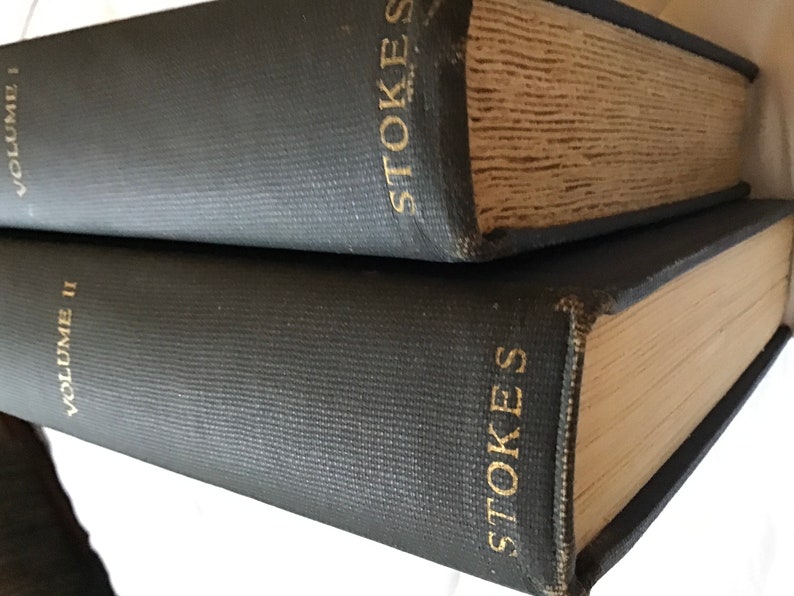 May include: Two dark blue hardcover books with gold lettering. The top book says "STOKES" and "VOLUME I". The bottom book says "STOKES" and "VOLUME II".