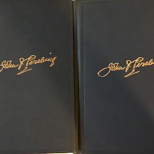 May include: Two dark blue book covers with gold lettering. The text on each cover reads "John J. Pershing".