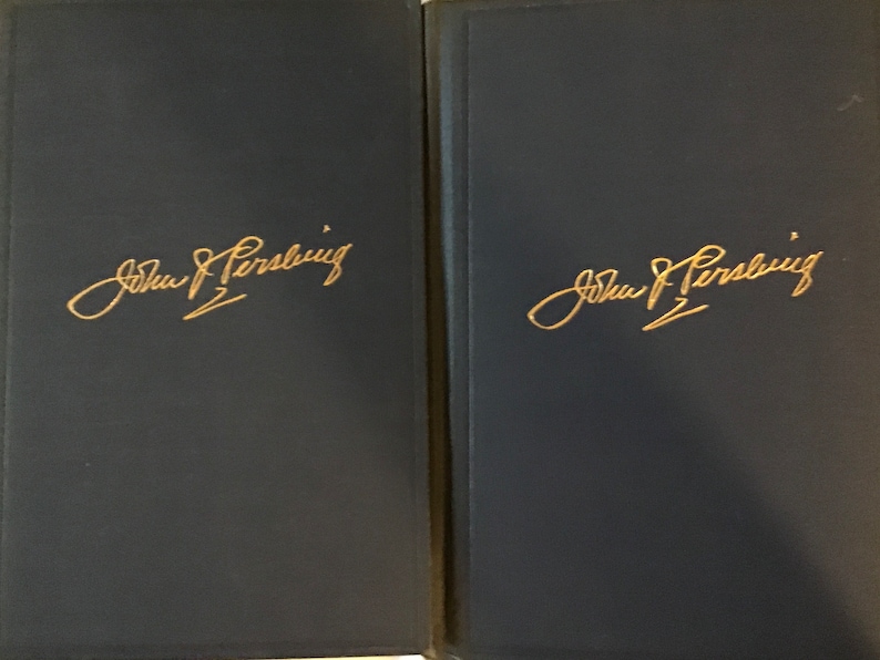 May include: Two dark blue book covers with gold lettering. The text on each cover reads "John J. Pershing".