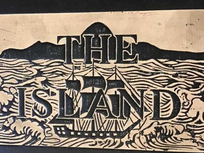 Op de afbeelding: Een zwart-witte illustratie van een schip dat op zee vaart met de tekst "THE ISLAND" erboven.