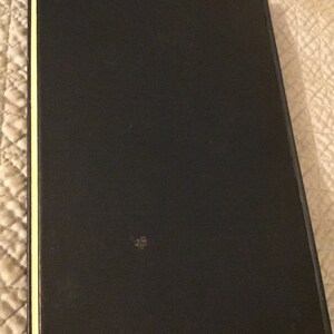 May include: A black hardback book with a gold spine.