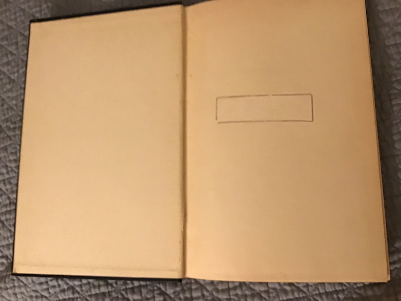 May include: A blank, cream-coloured book with a black spine. The book is open to a blank page with a pencil-drawn rectangle in the top right corner.