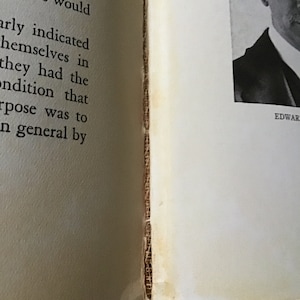 May include: A close-up of a book with a black and white photo of a man wearing a suit and hat. The text "EDWAR" is visible at the bottom of the page.