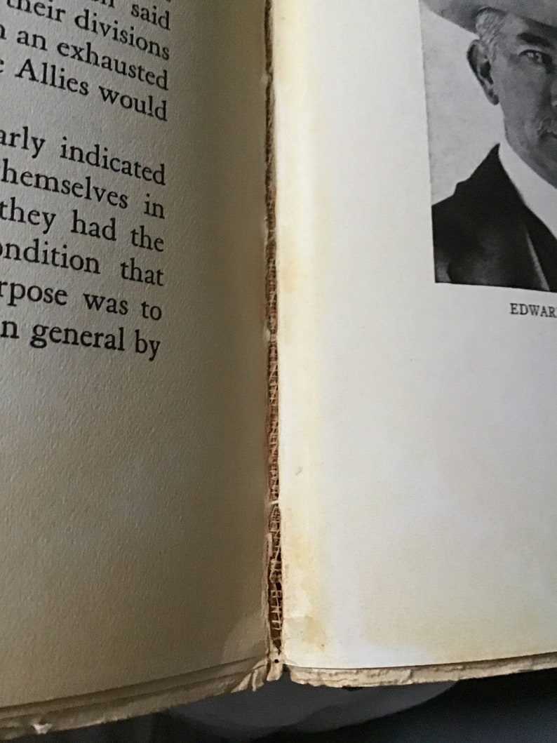 May include: A close-up of a book with a black and white photo of a man wearing a suit and hat. The text "EDWAR" is visible at the bottom of the page.