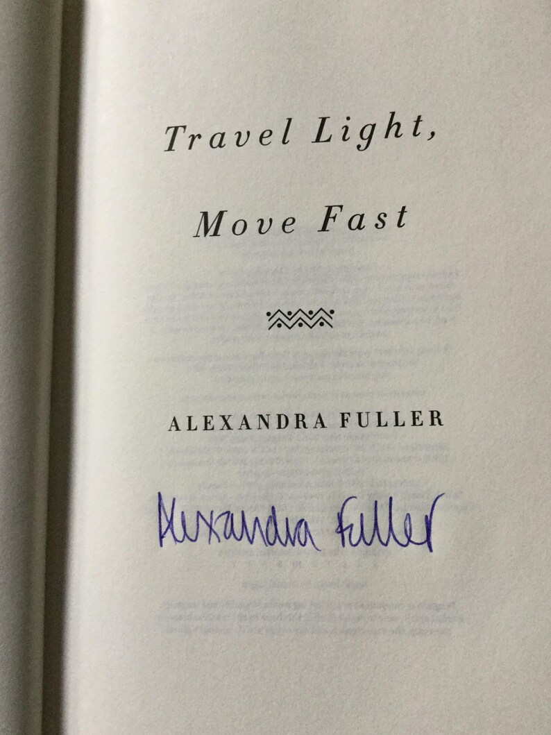 Puede incluir: P&aacute;gina de libro abierta con el texto "Travel Light, Move Fast" y el nombre de la autora, Alexandra Fuller. Una firma manuscrita en tinta azul aparece debajo del nombre de la autora.