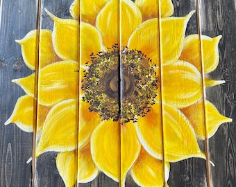 May include: A yellow sunflower painted on a wooden surface. The sunflower is painted in a realistic style with a dark brown center and yellow petals.