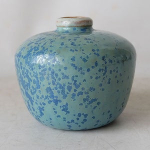 May include: A small, round, blue and green ceramic vase with a speckled glaze.