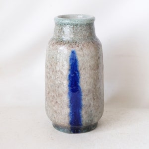 May include: A small, ceramic vase with a speckled, light gray glaze and a vertical blue stripe. The vase has a rounded body and a slightly flared opening.