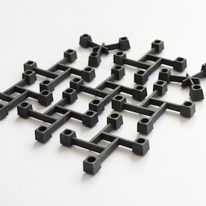 Op de afbeelding: Een zwarte metalen kaarsenhouder met een geometrisch ontwerp. De houder heeft meerdere armen die zich uitstrekken vanaf een centrale basis, waardoor een unieke en moderne uitstraling ontstaat.