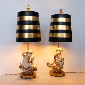 2 Hollywood Regency style 1980&#39;s ceramic monkey desk or table lamps. Two sitting monkeys and black/gold lamp shades