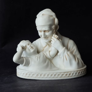 Vintage-Skulptur aus Biskuitporzellan eines Vaters mit seinem Kind. Der Vater tröstet sein Kind.