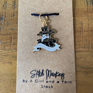 May include: Gold stitch marker featuring a black and white plague doctor with a scroll that reads "Wash Your Own Hands". The stitch marker is on a brown card with the text "Stitch Markers by A Girl and a Yarn Stash".