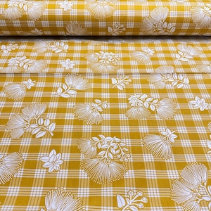 May include: Mustard yellow fabric with a white floral pattern and a plaid design. The fabric is rolled up and ready to be used for sewing projects. The floral pattern includes stylized flowers and leaves.