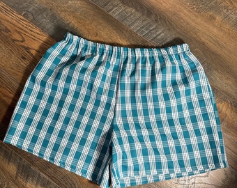 Peut inclure: Shorts à carreaux turquoise et blancs avec une taille élastique. Le short est fait d'un tissu léger et présente un motif à carreaux classique. Le vêtement est conçu pour le confort et les tenues décontractées.